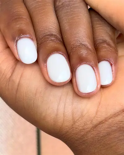 Unhas curtas arredondadas em gel branco, trabalho de Sílvia Paz